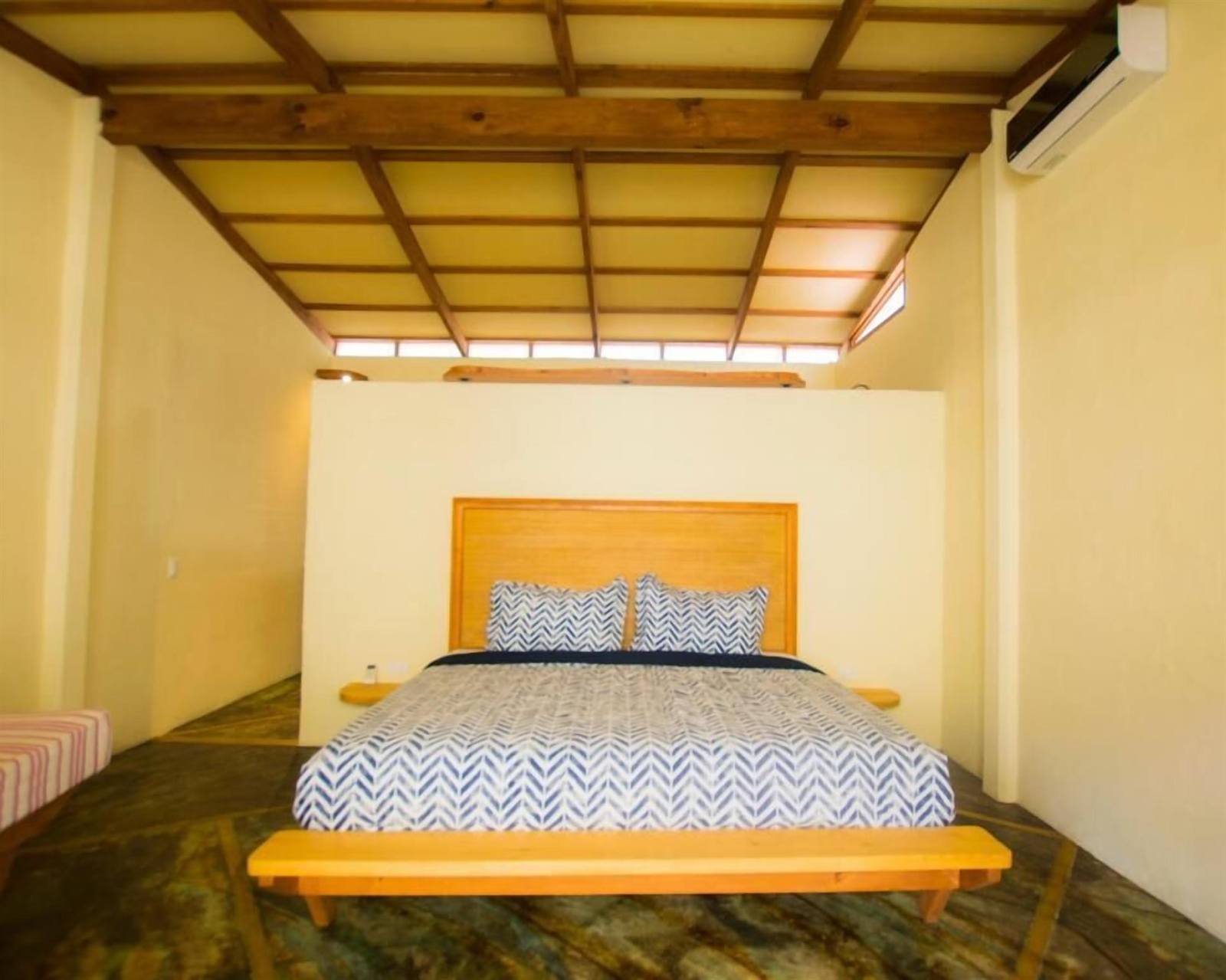 Galería Suites San Pancho: bedroom with a wooden platform bed and air conditioning